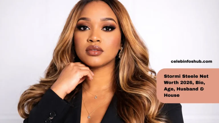 Stormi Steele posing confidently in a professional studio portrait, wearing a black blazer with soft glam makeup, glossy lips, and long honey-blonde waves against a clean background.
